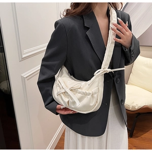 Detail of a chic cream hobo bag featuring pleated texture and a decorative bow design