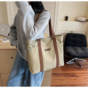 Gros plan d'un sac fourre-tout en toile beige avec sangles brunes et étiquette en cuir