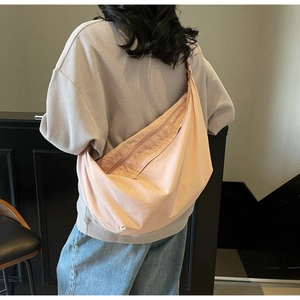 Rear view of a pink minimalist crescent crossbody bag worn by a model for a relaxed look