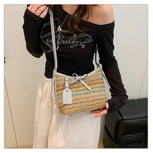 Detail of colorful woven shoulder bag featuring blue leather bow and fashion tag