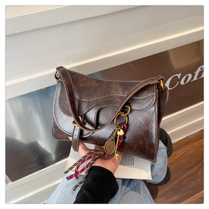 Detail of vintage brown saddle bag with white contrast stitching and gold metal charms