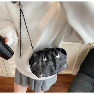 Close-up of charcoal gray pleated handbag with 3D silver butterfly charms and chain strap