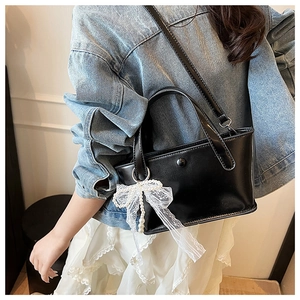 Borsa a secchiello in pelle nera con fiocco in pizzo bianco e ciondolo di perle su modella