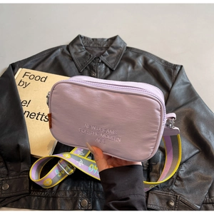 Detail of purple nylon crossbody bag featuring white embroidery and jacquard strap