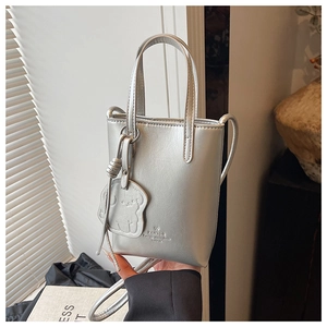 Close-up of a silver matte mini bucket bag with metallic luster and a cute puppy charm