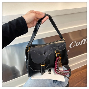 Detail of black leather saddle bag with white contrast stitching and gold ornaments