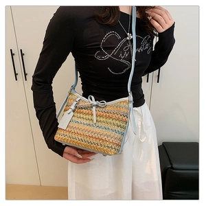 Detail of woven crossbody bag with colorful wave patterns and light blue leather bow trim