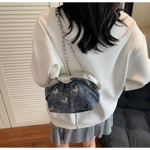Detail of blue denim pleated bucket bag featuring silver butterfly charms and chain