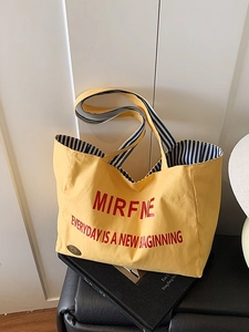 Yellow canvas tote bag with red lettering on a magazine in a bright minimalist setting