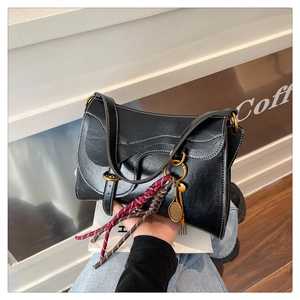 Detail of black vintage shoulder bag with wavy edge flap and tennis racket pendant