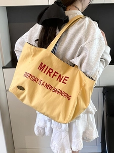 Large yellow canvas tote bag with red lettering and striped lining for daily commute