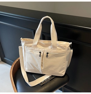 Detail of cream canvas tote bag showing vertical zippers on a black office chair