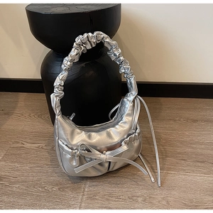 Détail d'un sac demi-lune argenté avec nœud plissé et bandoulière froncée tendance