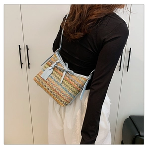 Detail view of woven crossbody bag with blue leather trim and bow on model