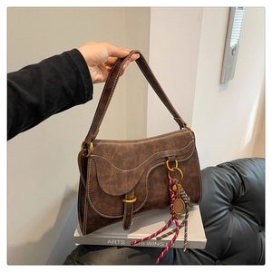 Detail of vintage brown saddle bag with white stitching and tennis racket pendant