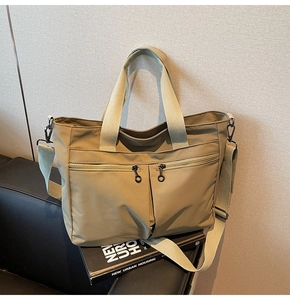 Detail of khaki tote bag featuring double front zip pockets and wide removable strap