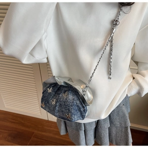 Fashionable denim crossbody bag with silver butterfly charms worn by a model