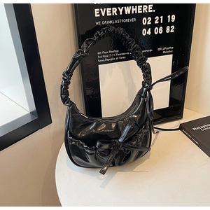 Détail du sac demi-lune noir brillant avec poignée plissée et nœud décoratif