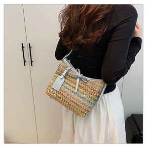 Detail of woven crossbody bag with light blue leather trim and fashion bow decoration