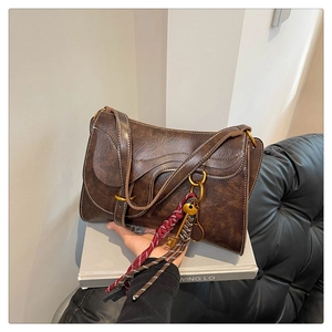 Detail of dark brown vintage saddle bag with woven rope charms and antique key ornaments