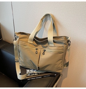 Close-up of khaki tote bag with dual front zipper pockets and durable woven handles