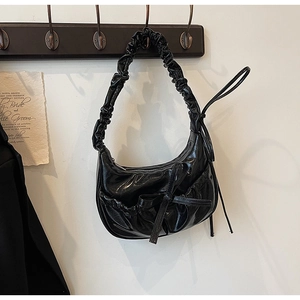 Gros plan d'un sac hobo noir brillant avec texture plissée et détail de poche à nœud