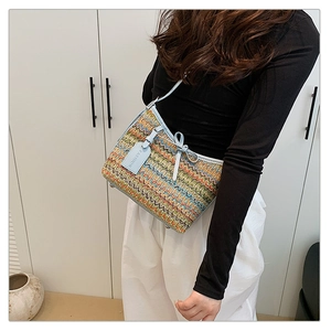 Detail of multi-color woven texture and light blue leather strap on a shoulder bag
