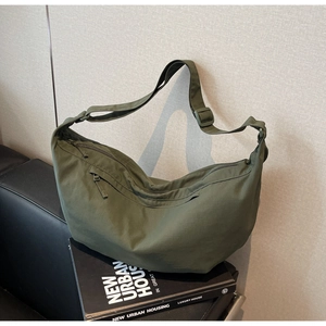 Detail of dark green nylon dumpling bag with adjustable strap and front zipper pocket