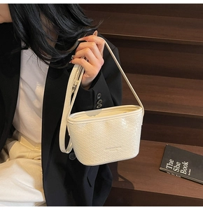 Close-up of white woven texture and brand logo on the bottom of this stylish shoulder bag