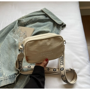 Detail of the cream nylon camera bag featuring a stylish wide patterned crossbody strap