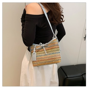 Detail view of woven crossbody bag with zigzag pattern, blue leather trim and bow