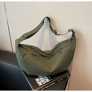 Detail of army green nylon crescent bag on a book with wide adjustable shoulder strap