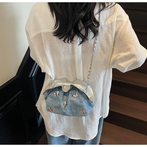 Blue denim cloud bag with silver butterfly charms worn cross-body by a model on stairs