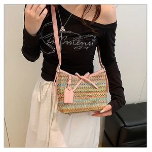 Detail of colorful woven shoulder bag with pink leather bow and FASHION charm