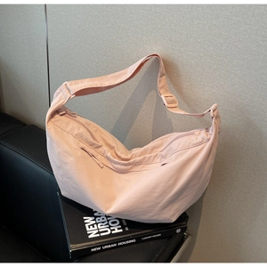 Macro detail of a light pink nylon crescent bag with adjustable strap and zip pocket
