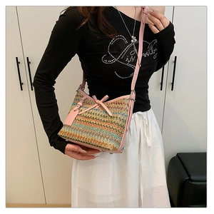 Detail of multi-color woven crossbody bag with pink leather trim and decorative bow