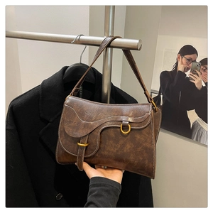 Detail of vintage brown saddle bag with white contrast stitching and antique metal rings