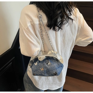 Detail of blue denim cloud bag with silver butterfly charm and metal chain strap