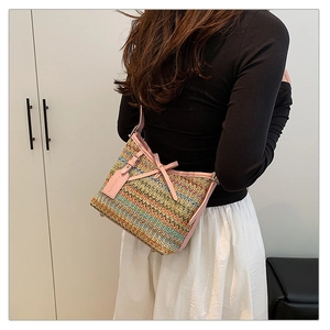 Close-up of a woven bohemian shoulder bag with pink bow detail and fashion tag