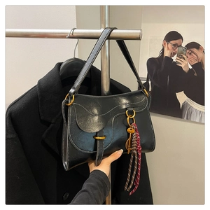 Close-up of black oil-wax leather saddle bag with white stitching and gold hardware detail