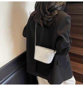 Detail of silver woven texture bucket bag styled over a minimalist black blazer