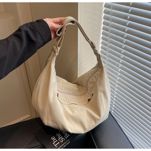 Detailed close-up of light beige crescent bag showing soft nylon texture and wide strap