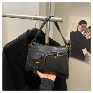 Close-up of black saddle bag featuring white contrast stitching and gold D-ring detail