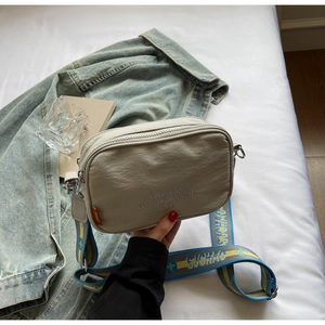Close-up of gray nylon camera bag with modern embroidery and floral woven strap