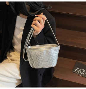 Macro shot of silver woven texture and embossed text on a trendy metallic shoulder bag