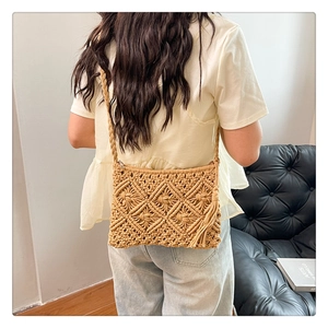 Detail of bohemian khaki knit bag featuring diamond pattern, fringe, and braided strap