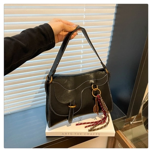 Close-up of black retro leather handbag with white contrast stitching and a unique charm