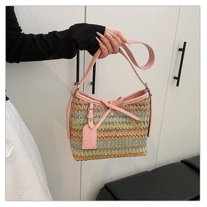 Detail of woven straw bucket bag featuring pink leather bow and fashion tag on the front