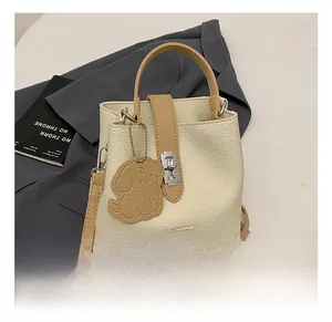 Close-up of creamy white lychee grain bucket bag with silver twist lock and puppy charm