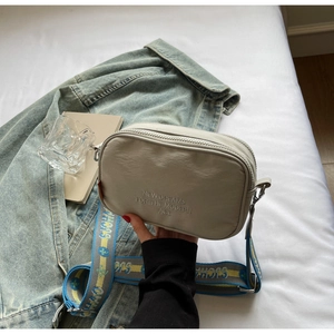 Detail of canvas camera bag featuring wide jacquard strap and modern ace lettering